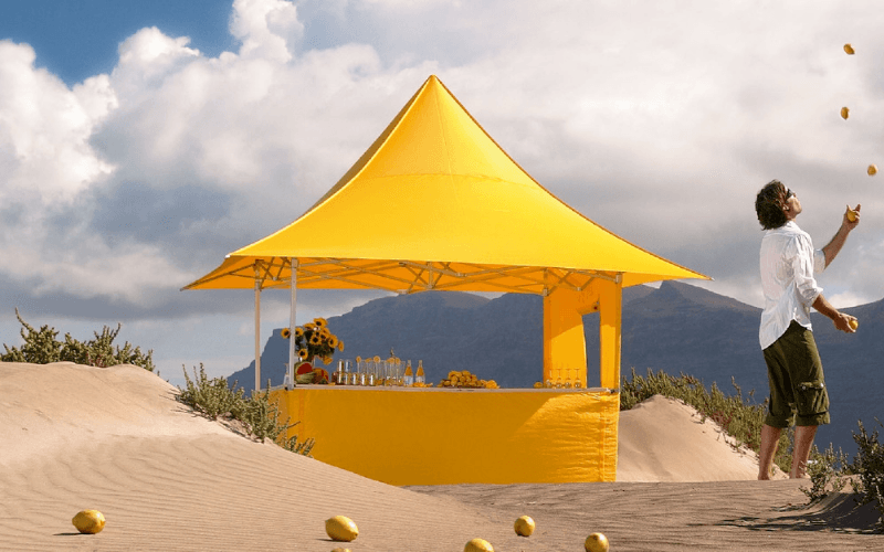 Yellow Folding Tent with awnings and half height side walls situated in a beach situation
