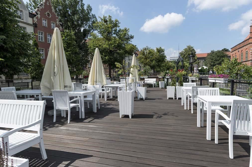 Al fresco riverside hospitality terrace with tables, armchairs and patio umbrellas